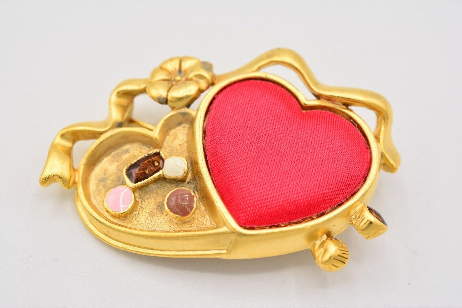 Gold heart-shaped jewelry box with red interior on a light gray background
