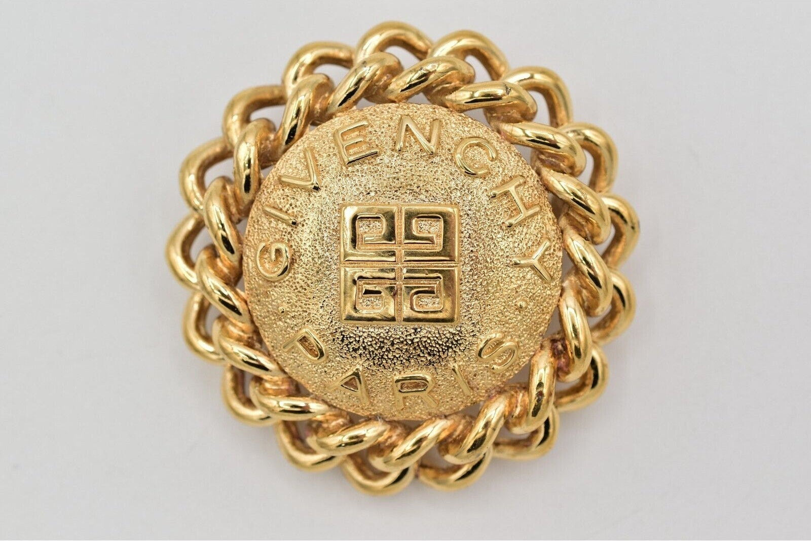 Gold chain belt buckle with 'Givenchy' branding on a gray background
