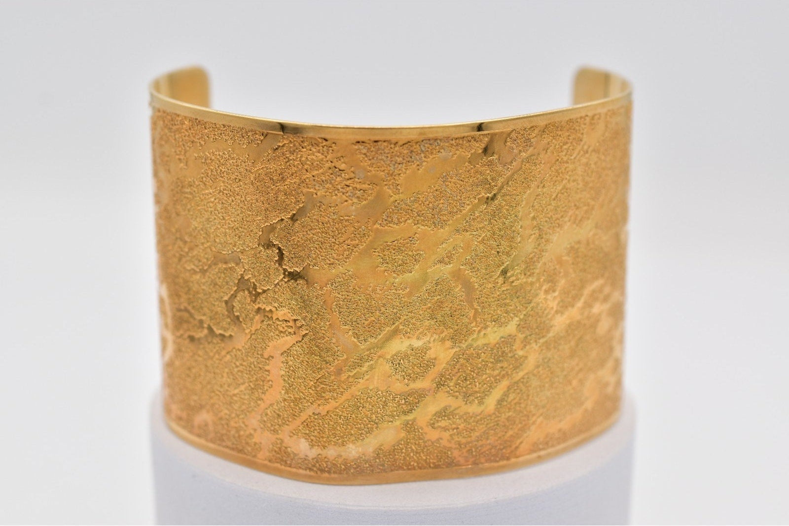 Gold textured cuff bracelet on a light gray background