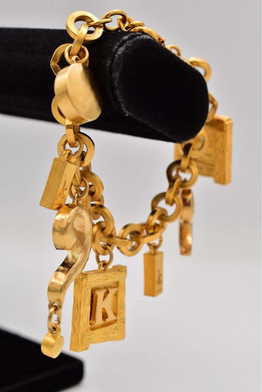 Gold bracelet with charms on a black stand against a gray background