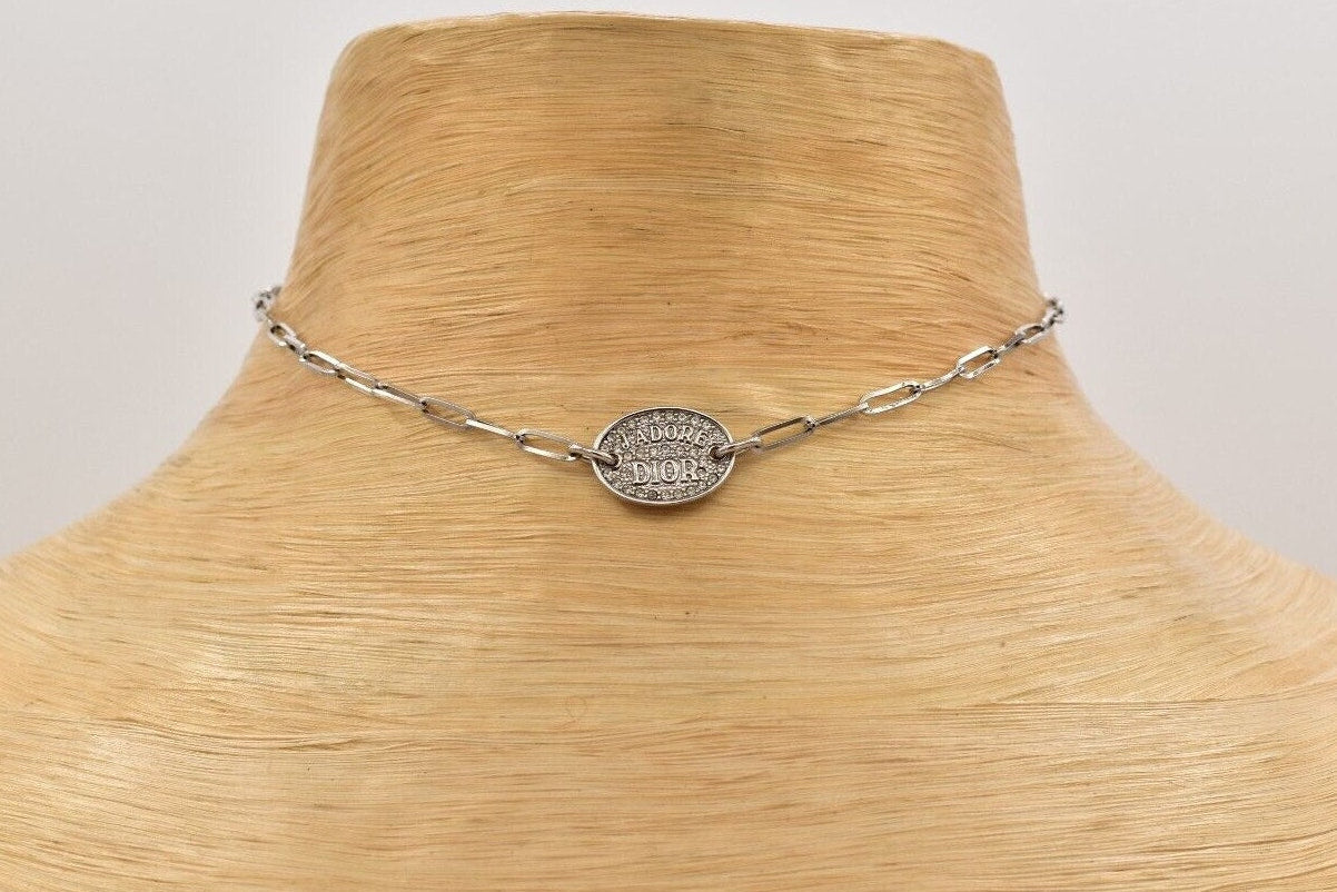 Vintage Dior J'Adore silver chain necklace with a round pendant on a wooden mannequin.