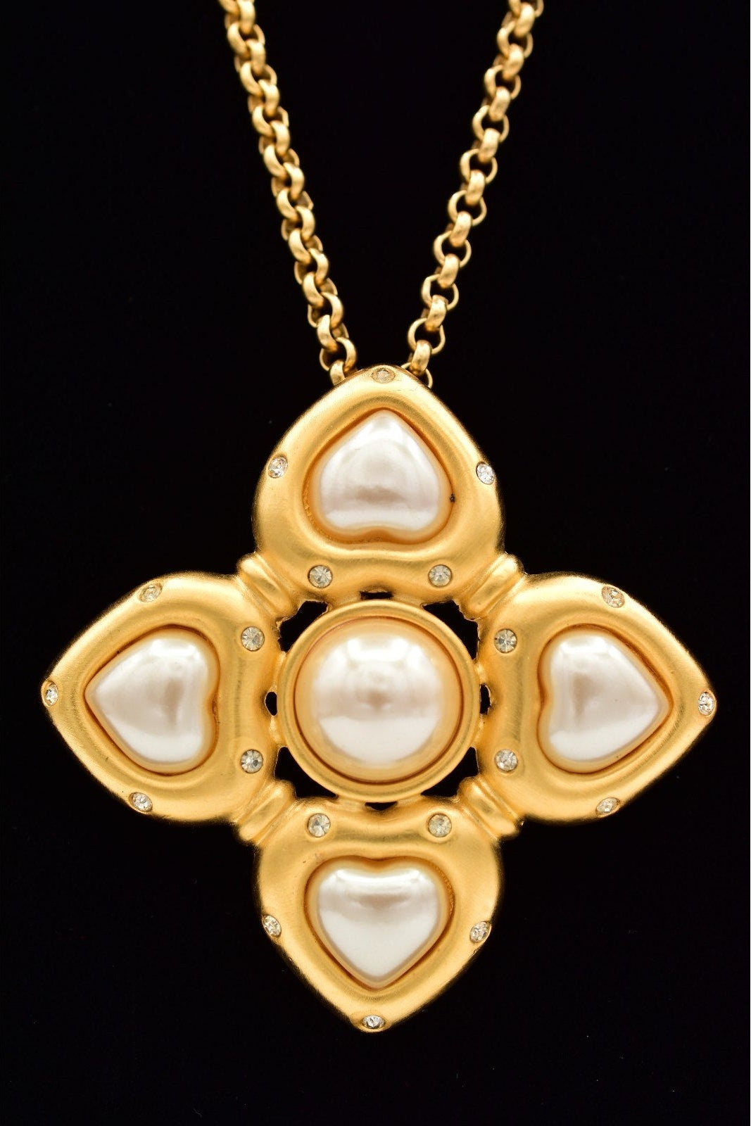 Gold necklace with a heart-shaped pendant on a black background