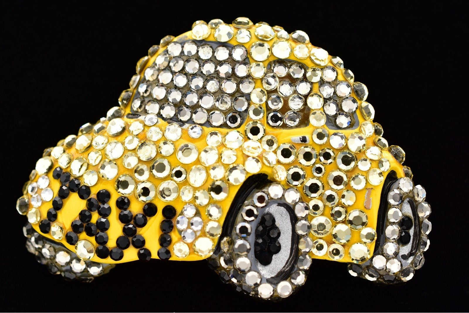 Decorative brooch with rhinestones shaped like a car on a black background