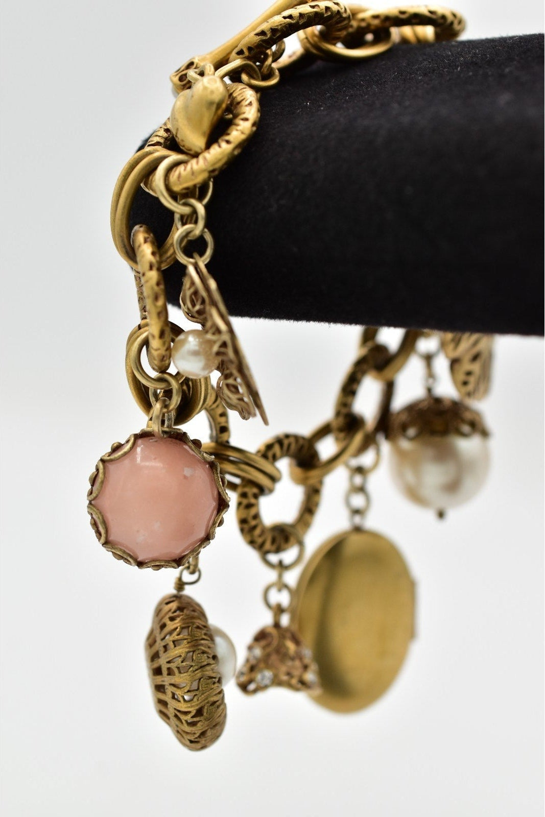 Gold charm bracelet with various charms on a white background