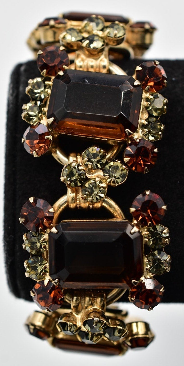 Bracelet with gemstones on a black stand against a white background