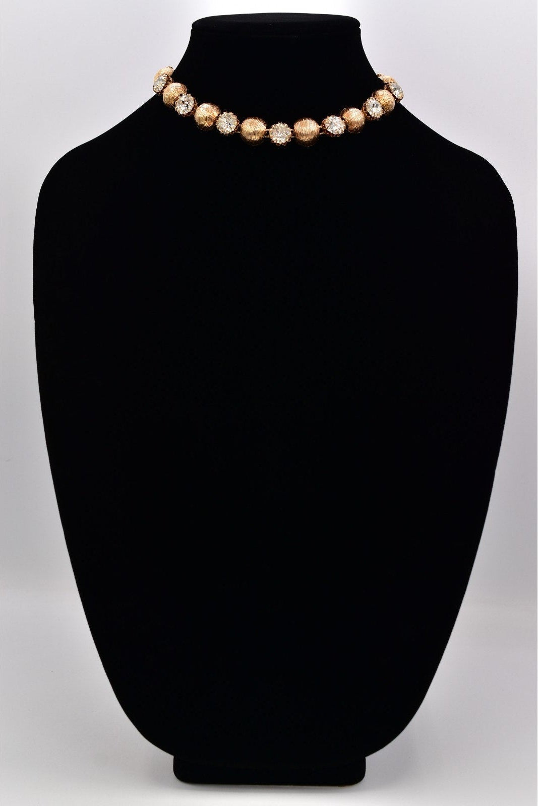 Necklace on a black mannequin bust with a plain background