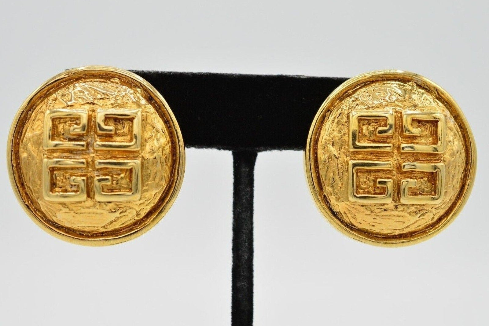 Pair of gold earrings with intricate design on a white background