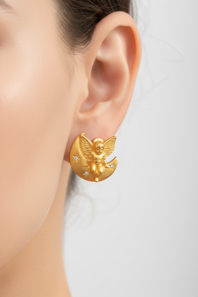 Gold charm of a cherub on a moon with a ruler for scale on a white background