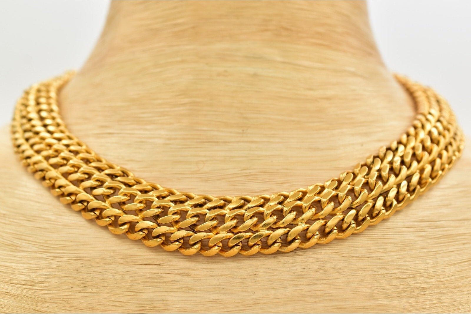 Gold chain necklace on a mannequin neck against a white background