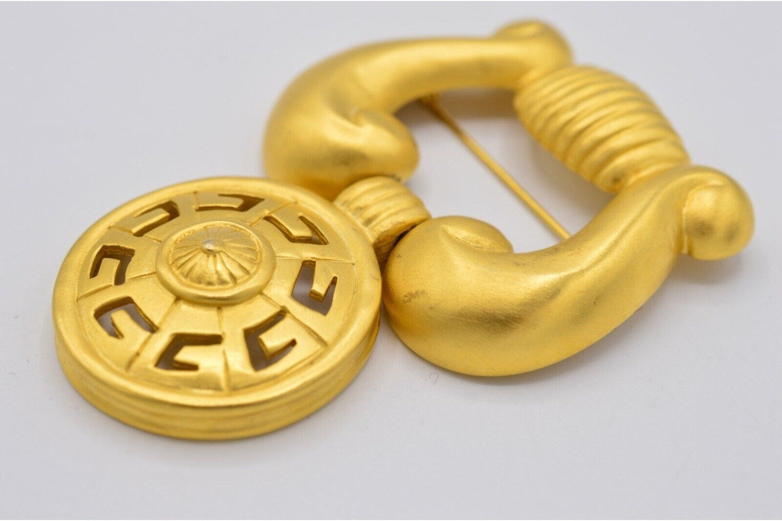 Vintage Givenchy door knocker brooch laying on a black background