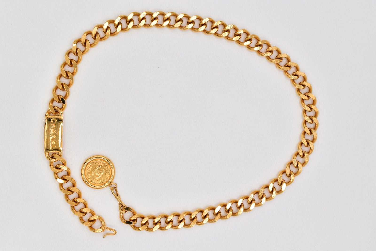 Gold chain bracelet on a light gray background
