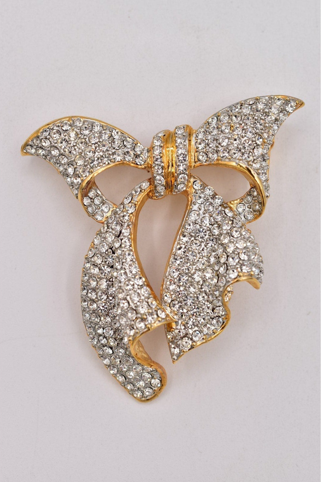 Gold and crystal butterfly-shaped brooch on a light gray background